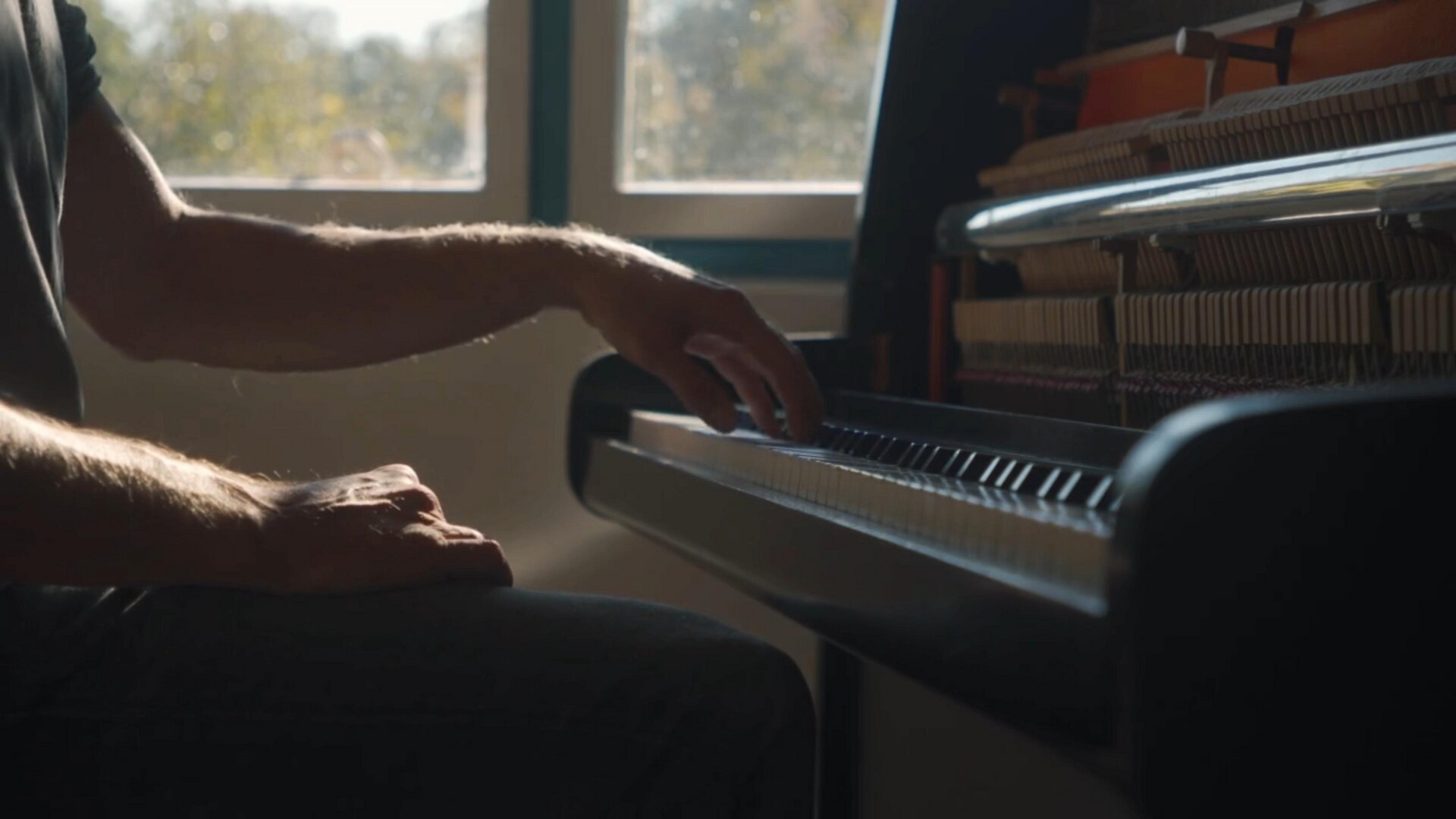 Hands poised over the piano keys, illuminated by natural light, capturing a moment of musical inspiration.