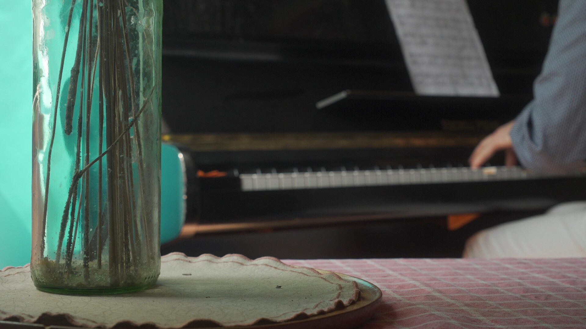 A glass art piece rests before a grand piano, suggesting the harmony of music and creativity.