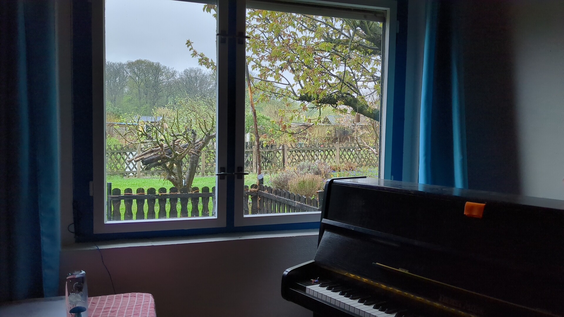 A grand piano positioned by a window overlooking a serene, natural landscape.