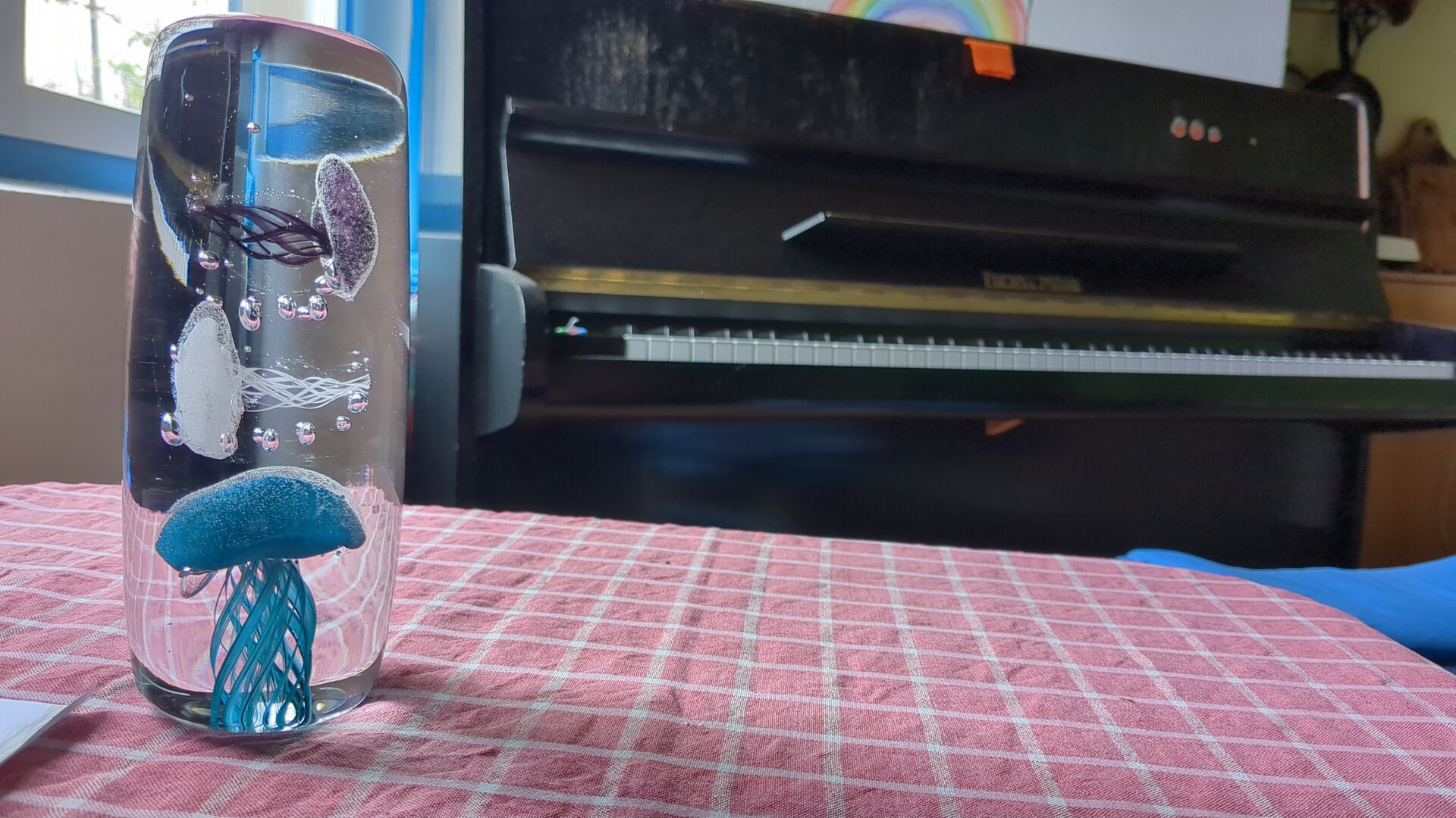 Decorative glass vase and a grand piano displayed on a checkered tablecloth.