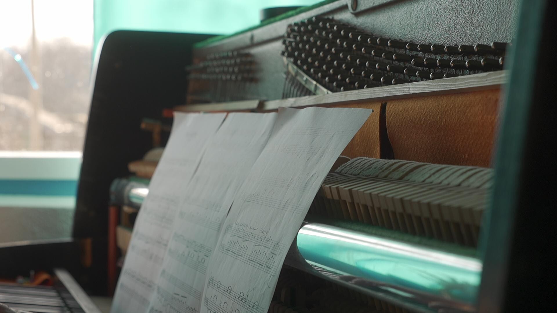 Sheet music and piano mechanisms bathed in soft natural light, evoking the romance of musical composition.