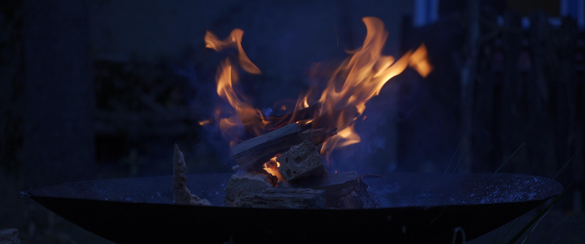 Ephemeral glow of fire and smoke burning on a dark surface.